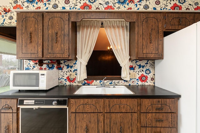 2311 E Meadow Dr, Springfield, MO 65804 - kitchen with white microwave, dishwasher, dark countertops, wallpapered walls, and brown cabinetry