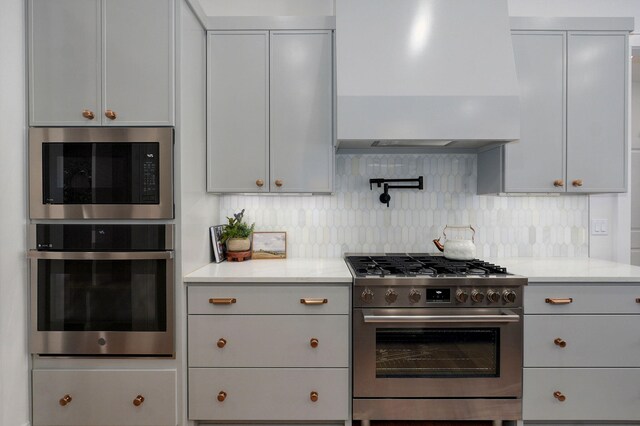 3945 E Woodhue St, Springfield, MO 65802 - kitchen featuring appliances with stainless steel finishes, premium range hood, light countertops, decorative backsplash, and gray cabinetry