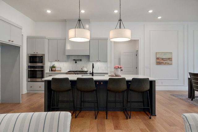 3945 E Woodhue St, Springfield, MO 65802 - kitchen featuring stainless steel oven, light countertops, built in microwave, decorative backsplash, and a center island with sink