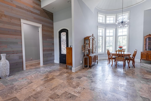 6323 Creeksedge Ct, Ozark, MO 65721 - foyer featuring stone tile flooring, a towering ceiling, wooden walls, an accent wall, and a chandelier