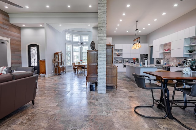 6323 Creeksedge Ct, Ozark, MO 65721 - living room featuring a high ceiling, stone finish flooring, a chandelier, recessed lighting, and wooden walls
