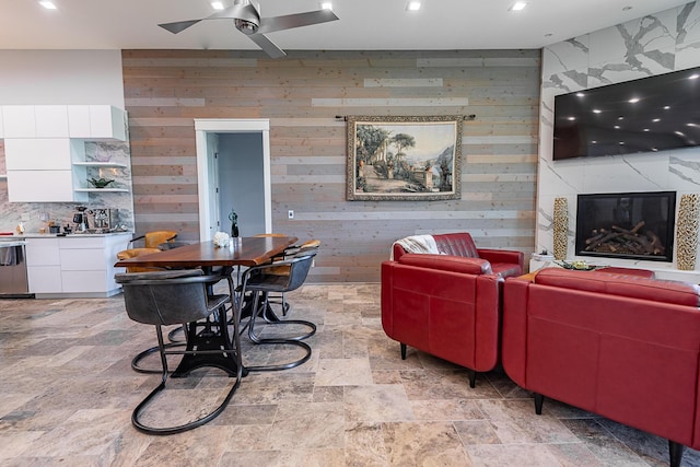 6323 Creeksedge Ct, Ozark, MO 65721 - dining space featuring a ceiling fan, a premium fireplace, wooden walls, light stone finish floors, and recessed lighting