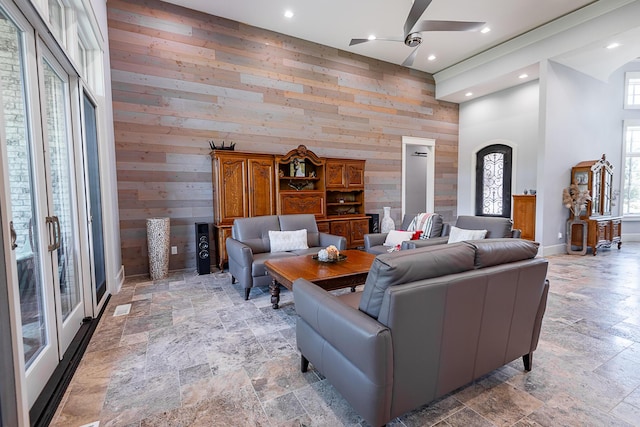 6323 Creeksedge Ct, Ozark, MO 65721 - living room with stone tile floors, plenty of natural light, a ceiling fan, wooden walls, and a towering ceiling