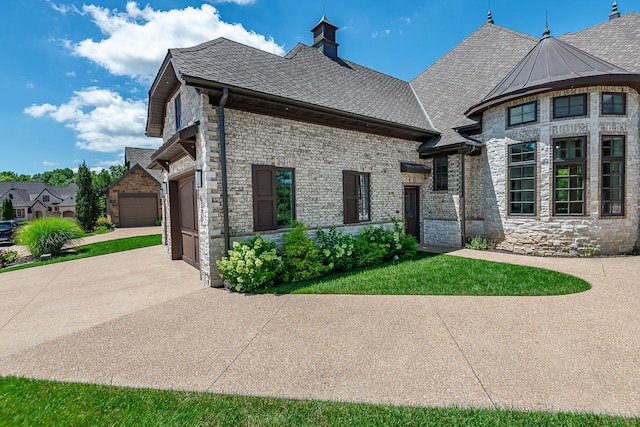 6323 Creeksedge Ct, Ozark, MO 65721 - view of side of home featuring driveway, stone siding, an attached garage, and roof with shingles