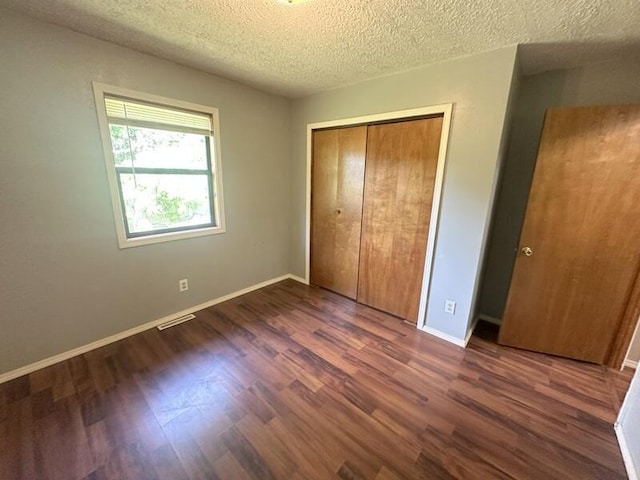2201 S 18th Ave, Ozark, MO 65721 - unfurnished bedroom featuring dark wood-style flooring, a closet, and a textured ceiling