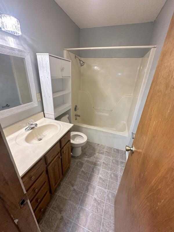 2201 S 18th Ave, Ozark, MO 65721 - bathroom featuring vanity, tub / shower combination, and a textured ceiling