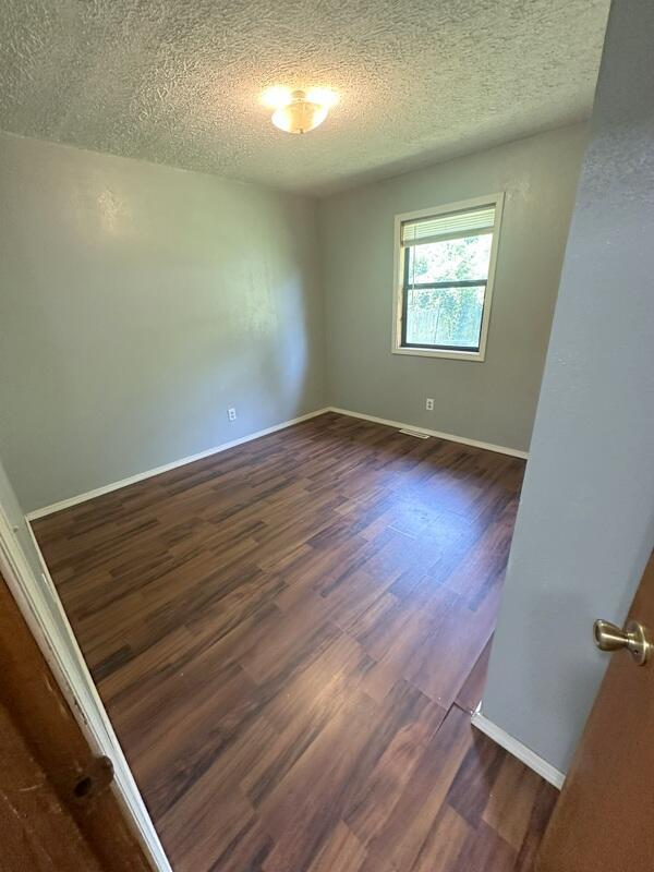 2201 S 18th Ave, Ozark, MO 65721 - unfurnished room with a textured ceiling and dark wood-style floors