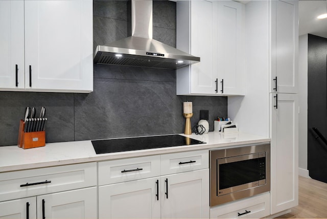 12163 State Highway Tt, Republic, MO 65738 - kitchen featuring wall chimney range hood, black electric cooktop, stainless steel microwave, tasteful backsplash, and white cabinets