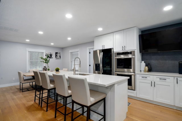 12163 State Highway Tt, Republic, MO 65738 - kitchen featuring stainless steel appliances, light wood-style floors, a center island with sink, a kitchen bar, and recessed lighting