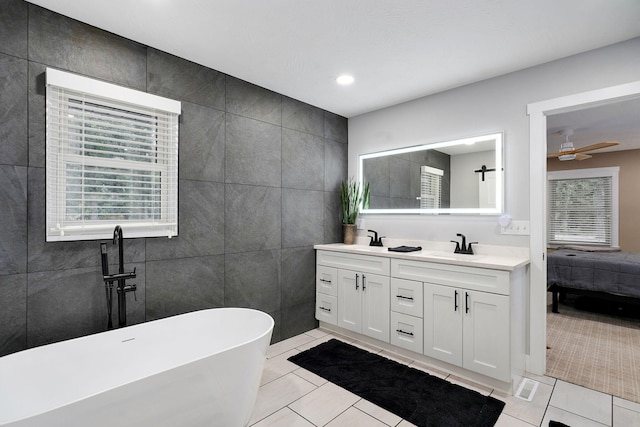 12163 State Highway Tt, Republic, MO 65738 - ensuite bathroom featuring tile walls, tile patterned floors, a freestanding tub, double vanity, and ceiling fan