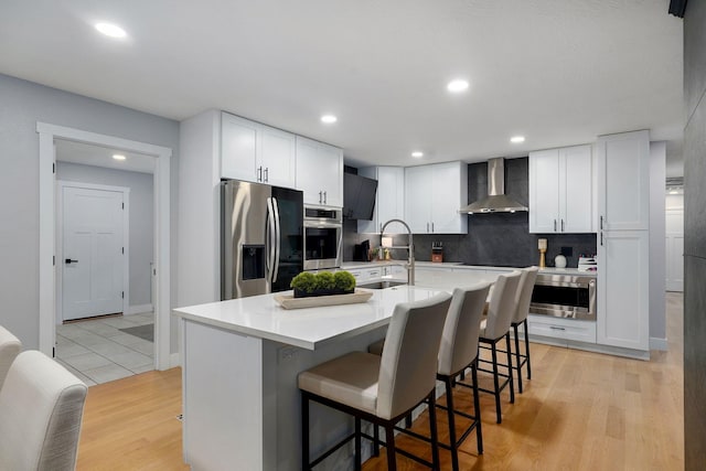 12163 State Highway Tt, Republic, MO 65738 - kitchen with wall chimney range hood, stainless steel appliances, a breakfast bar, tasteful backsplash, and white cabinetry