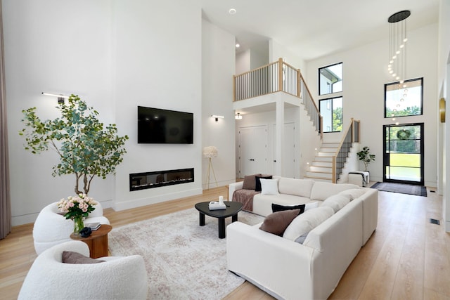 104 Walnut Hill Ln, Ozark, MO 65721 - living room featuring a towering ceiling, light wood finished floors, stairs, and a glass covered fireplace