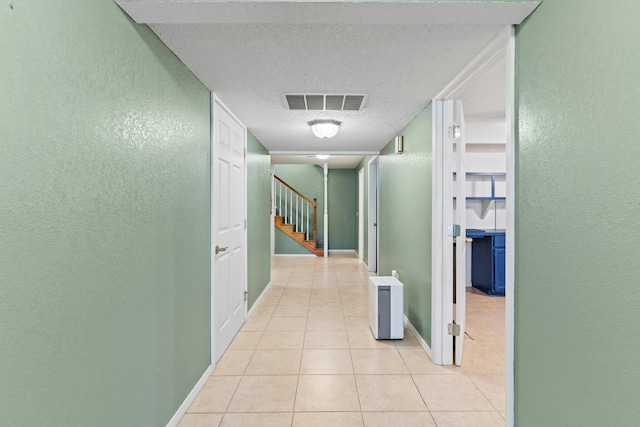 8756 W Farm Rd Unit 124, Springfield, MO 65802 - hallway with a textured ceiling, a textured wall, light tile patterned floors, and stairway