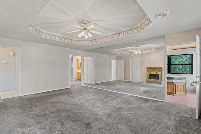 8756 W Farm Rd Unit 124, Springfield, MO 65802 - unfurnished living room featuring ceiling fan, a textured ceiling, carpet, a brick fireplace, and a tray ceiling