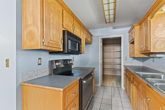 8756 W Farm Rd Unit 124, Springfield, MO 65802 - kitchen with black appliances, a textured ceiling, dark countertops, light tile patterned flooring, and brown cabinetry