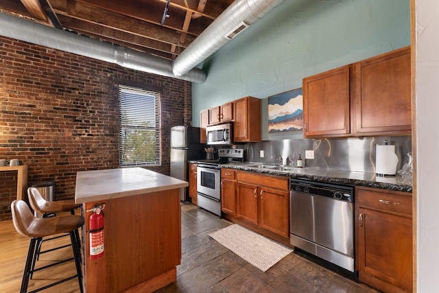 509 W Olive St Unit 206, Springfield, MO 65806 - kitchen with stainless steel appliances, brown cabinetry, a breakfast bar area, dark countertops, and tasteful backsplash