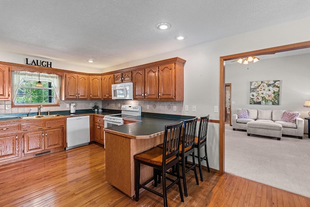 2602 S 15th Ave, Ozark, MO 65721 - kitchen featuring white appliances, brown cabinets, dark countertops, a peninsula, and light wood finished floors