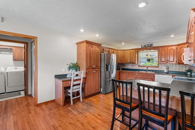 2602 S 15th Ave, Ozark, MO 65721 - kitchen featuring stainless steel fridge with ice dispenser, washer and dryer, a textured ceiling, light wood-type flooring, and brown cabinetry