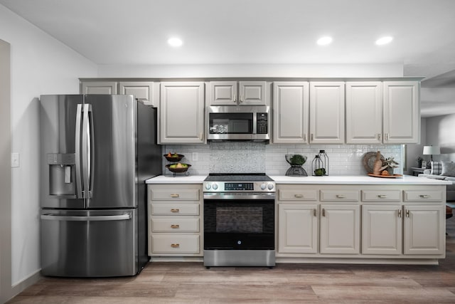 620 E Summit St, Bolivar, MO 65613 - kitchen with stainless steel appliances, light countertops, backsplash, light wood-type flooring, and recessed lighting