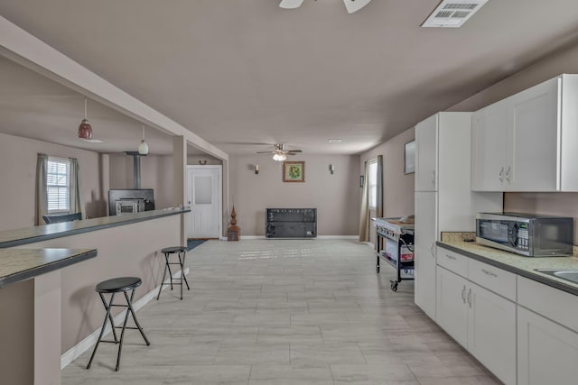 3197 S Grand Ave, Carthage, MO 64836 - kitchen with stainless steel microwave, a ceiling fan, a breakfast bar, open floor plan, and white cabinetry