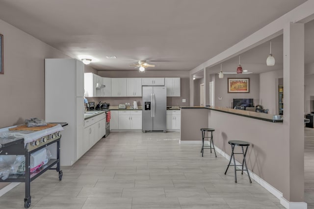3197 S Grand Ave, Carthage, MO 64836 - kitchen featuring stainless steel appliances, a breakfast bar area, ceiling fan, white cabinets, and dark countertops