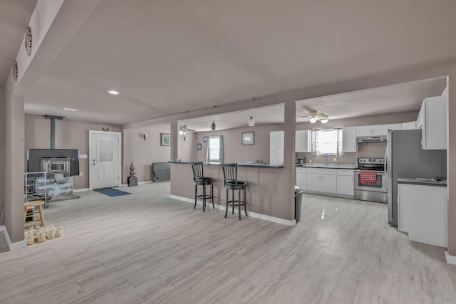 3197 S Grand Ave, Carthage, MO 64836 - kitchen with stainless steel range with electric stovetop, a ceiling fan, under cabinet range hood, open floor plan, and white cabinets