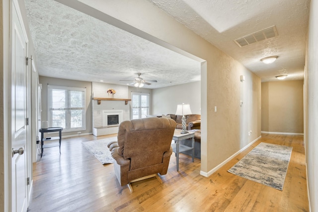 3477 W Broadmoor Ct, Springfield, MO 65807 - living area featuring a textured ceiling, light wood-style floors, ceiling fan, and a brick fireplace