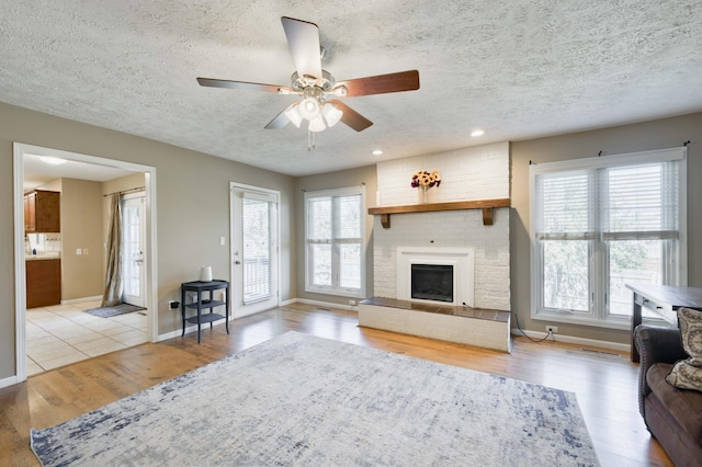 3477 W Broadmoor Ct, Springfield, MO 65807 - living room featuring a textured ceiling, wood finished floors, ceiling fan, a brick fireplace, and recessed lighting