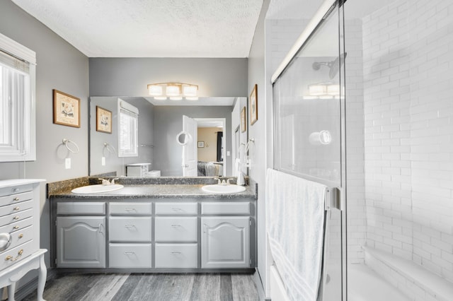 3477 W Broadmoor Ct, Springfield, MO 65807 - bathroom featuring double vanity, a shower with shower door, wood finished floors, and a textured ceiling