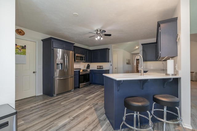360 Durango Ln, Billings, MO 65610 - kitchen featuring appliances with stainless steel finishes, a peninsula, a ceiling fan, a breakfast bar area, and light wood finished floors