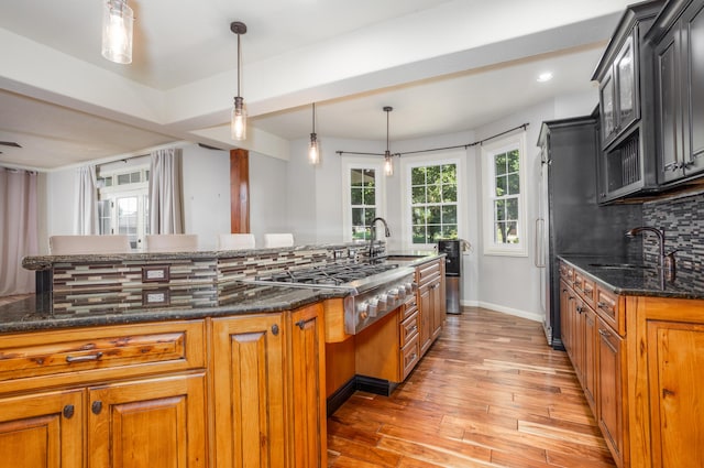 4225 E Crosswinds Pl, Springfield, MO 65809 - kitchen featuring tasteful backsplash, light wood-style floors, dark stone countertops, stainless steel gas stovetop, and brown cabinets