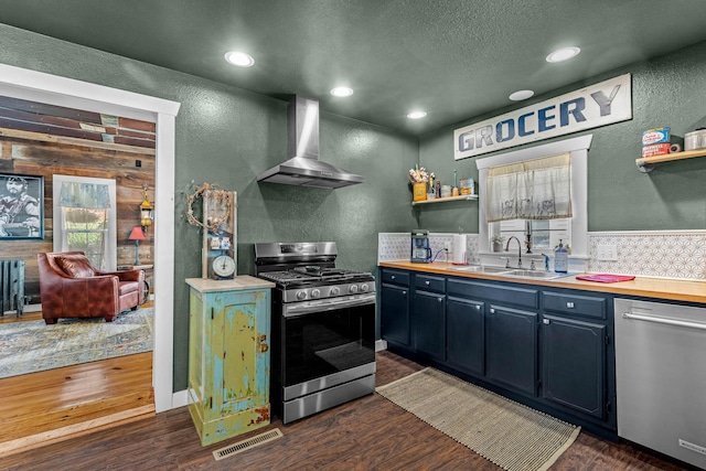 208 E Washington St, Pierce City, MO 65723 - kitchen with appliances with stainless steel finishes, wall chimney exhaust hood, a textured wall, open shelves, and dark wood-style flooring