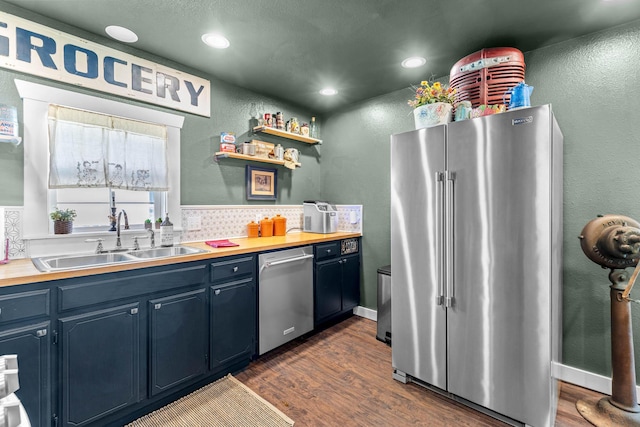 208 E Washington St, Pierce City, MO 65723 - kitchen featuring appliances with stainless steel finishes, blue cabinetry, dark wood finished floors, a textured wall, and tasteful backsplash