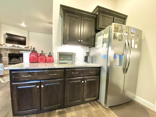 1113 Chesterfield Dr, Webb City, MO 64870 - kitchen featuring stainless steel fridge with ice dispenser, light wood-style floors, decorative backsplash, light stone countertops, and dark brown cabinetry