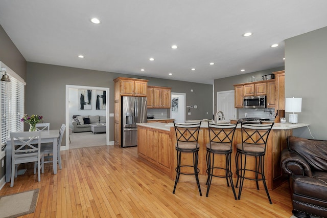 3931 E Stanford St, Springfield, MO 65809 - kitchen featuring appliances with stainless steel finishes, a peninsula, light wood finished floors, light countertops, and recessed lighting