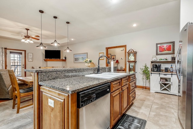 2419 W Deerbrooke Trl, Ozark, MO 65721 - kitchen featuring appliances with stainless steel finishes, brown cabinetry, a kitchen island with sink, a ceiling fan, and light tile patterned flooring