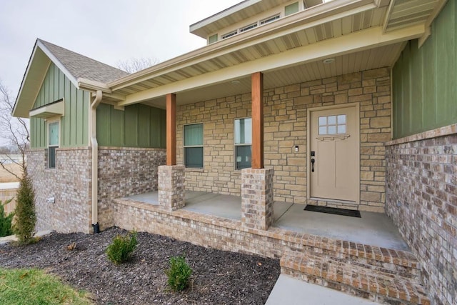 4212 Tuscany Cir, Ozark, MO 65721 - view of exterior entry featuring board and batten siding, covered porch, a shingled roof, stone siding, and brick siding