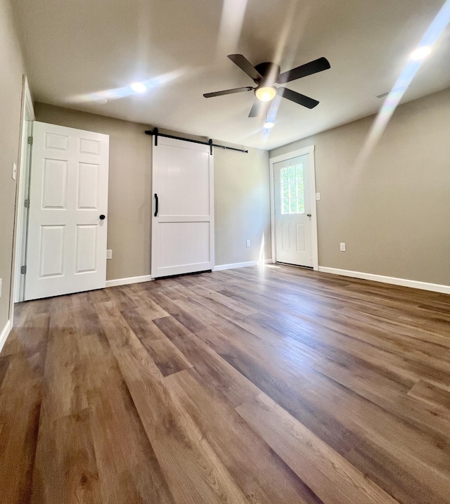 711 W Woodbine Rd, Ash Grove, MO 65604 - unfurnished bedroom with a barn door, wood finished floors, and ceiling fan