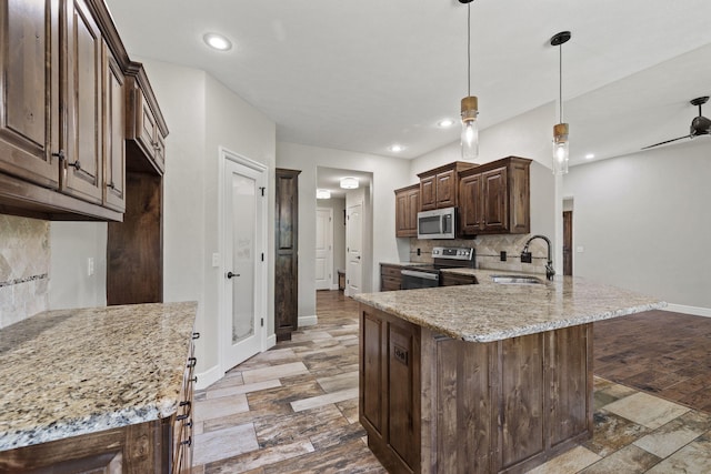 5323 S Carson St, Battlefield, MO 65619 - kitchen with appliances with stainless steel finishes, backsplash, light stone counters, a peninsula, and dark brown cabinetry