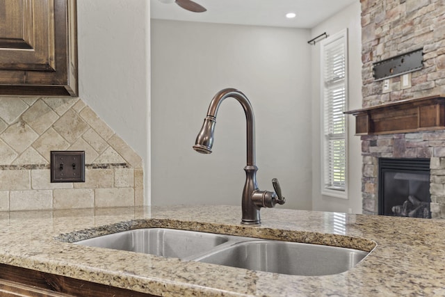 5323 S Carson St, Battlefield, MO 65619 - kitchen featuring dark brown cabinets, light stone countertops, a stone fireplace, and decorative backsplash