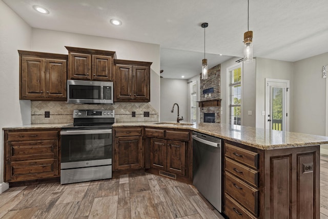 5323 S Carson St, Battlefield, MO 65619 - kitchen with appliances with stainless steel finishes, backsplash, a stone fireplace, a peninsula, and dark brown cabinetry