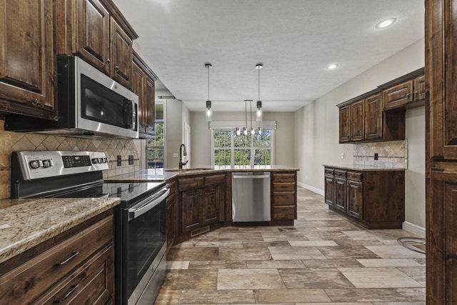 5323 S Carson St, Battlefield, MO 65619 - kitchen with stainless steel appliances, dark brown cabinets, tasteful backsplash, light stone countertops, and hanging light fixtures