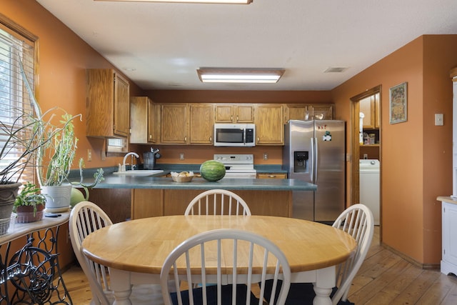 508 N Cherry Cir, Nixa, MO 65714 - kitchen with stainless steel appliances, dark countertops, light wood-style floors, a peninsula, and washer / clothes dryer
