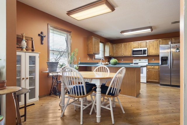 508 N Cherry Cir, Nixa, MO 65714 - kitchen with appliances with stainless steel finishes, a peninsula, light wood-style flooring, dark countertops, and brown cabinetry