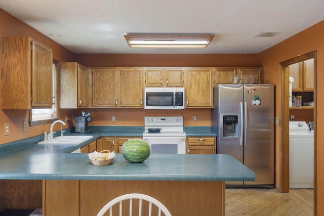 508 N Cherry Cir, Nixa, MO 65714 - kitchen featuring stainless steel appliances, a peninsula, washer and dryer, light wood-type flooring, and brown cabinetry