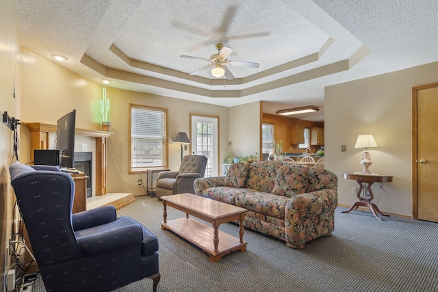 508 N Cherry Cir, Nixa, MO 65714 - carpeted living area with a ceiling fan, a tray ceiling, a textured ceiling, and a tiled fireplace