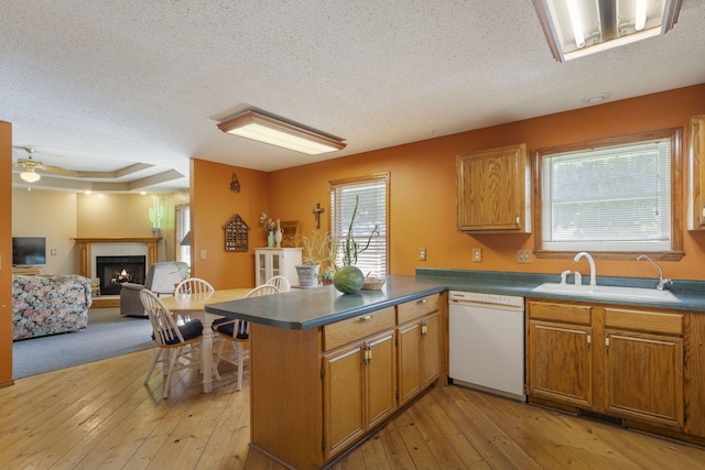 508 N Cherry Cir, Nixa, MO 65714 - kitchen featuring dishwasher, a textured ceiling, a peninsula, a tiled fireplace, and light wood-type flooring