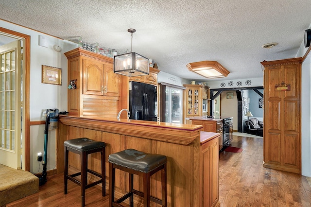 1343 Woodlawn Ave, Mount Vernon, MO 65712 - kitchen with black refrigerator with ice dispenser, a peninsula, light wood finished floors, a textured ceiling, and brown cabinetry