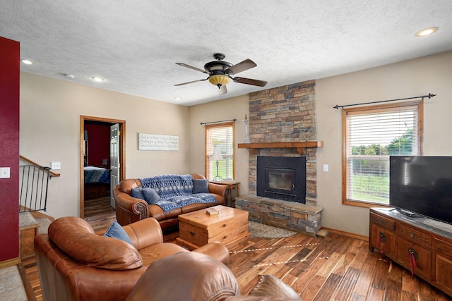 8404 Fossilsaurus Ln, Ash Grove, MO 65604 - living area with wood finished floors, a ceiling fan, a textured ceiling, a stone fireplace, and recessed lighting