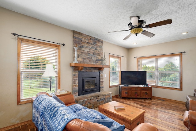 8404 Fossilsaurus Ln, Ash Grove, MO 65604 - living area with a ceiling fan, wood-type flooring, a textured ceiling, and a stone fireplace